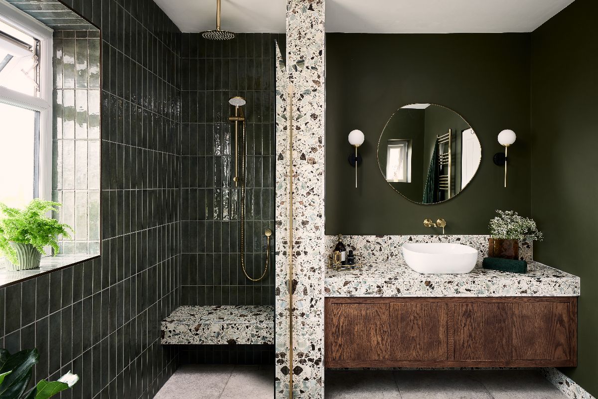Green bathroom design with a walk-in shower and vanity area with a wood unit, speckled surfaces, and minimalist decor.