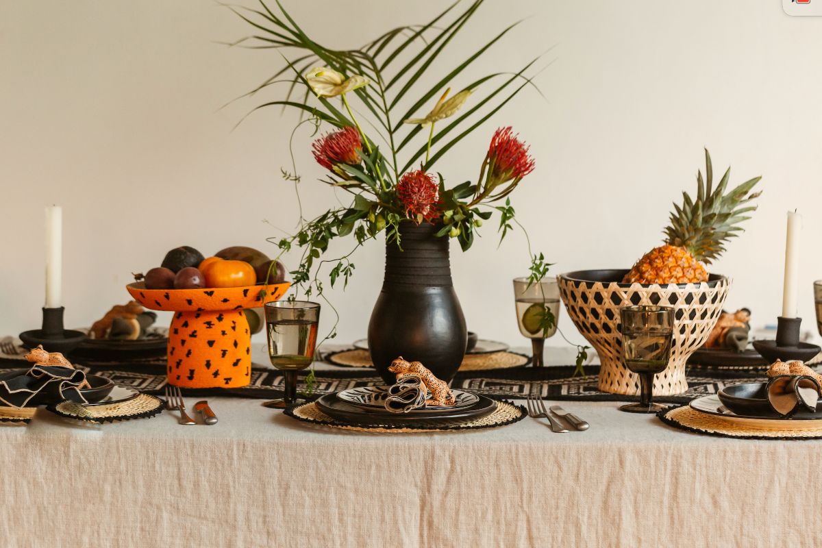 An autumn table scheme with orange fruit plate, black fruit bowl, black vase, and matching crockery.