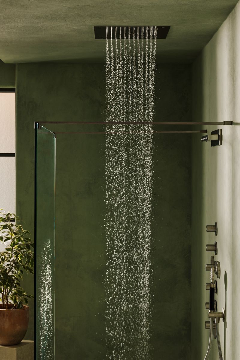 Closeup of a green wetroom with rainfall showerhead and nickel brassware.