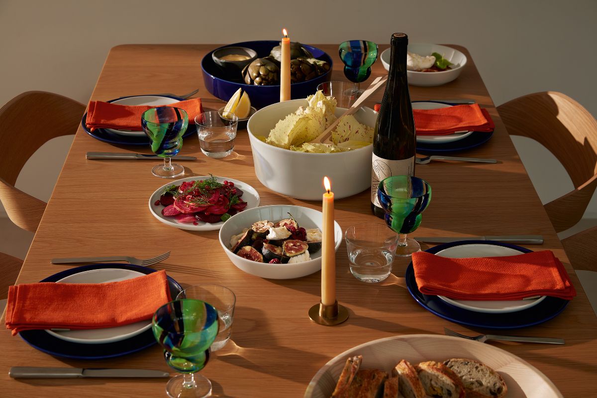 A simple autumn table scheme with blue and white plates, white and navy serving bowls, orange napkins and pale yellow candlesticks.