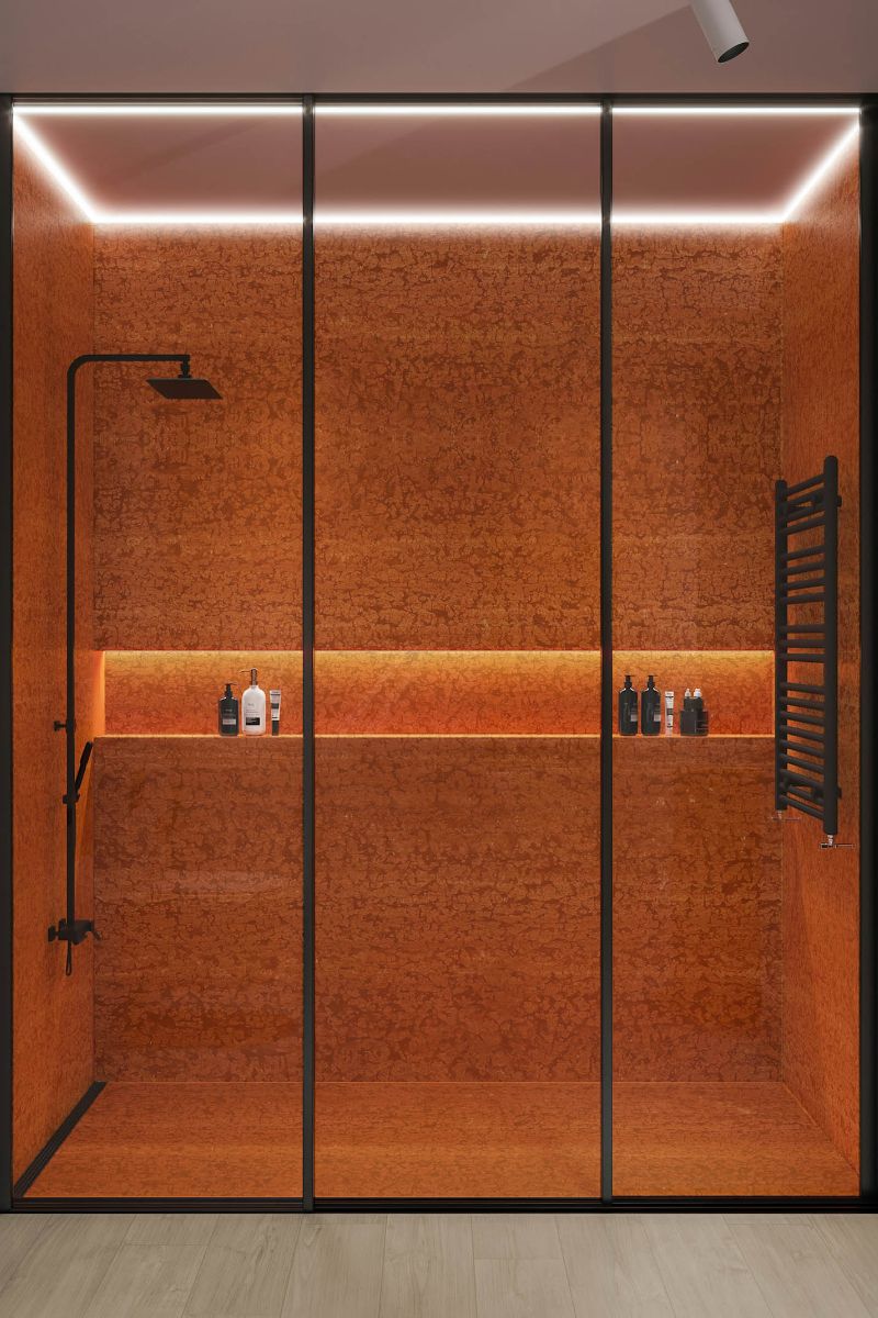 Shower enclosure with red marble, storage niche and black brassware.
