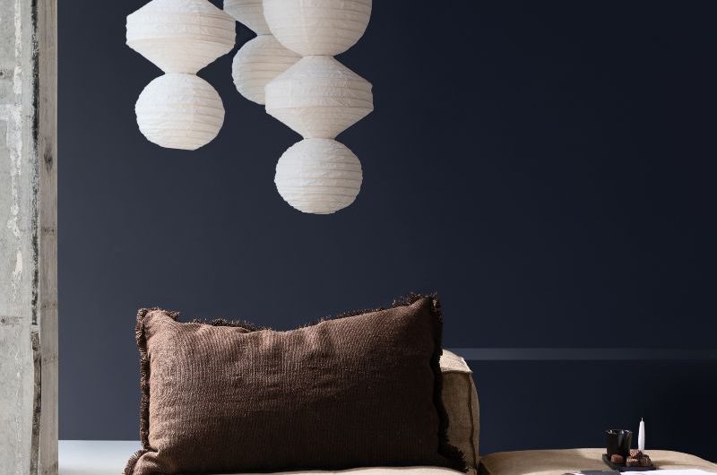 A cosy seating spot with a plush sofa and inky blue wall paint.