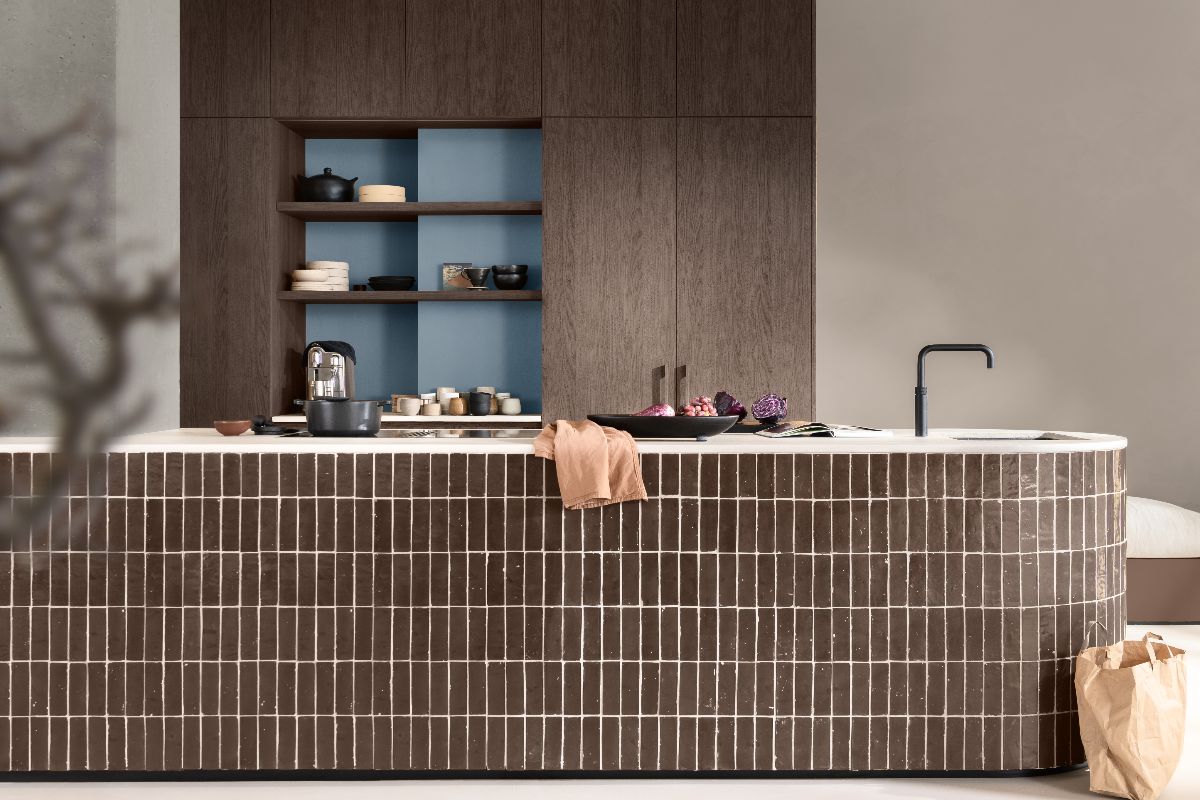 A modern kitchen with a tiled island and wood cabinetry.