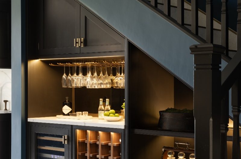A compact bar area, with wall-mounted glass storage, bottle rack, and built-in bottle fridge.
