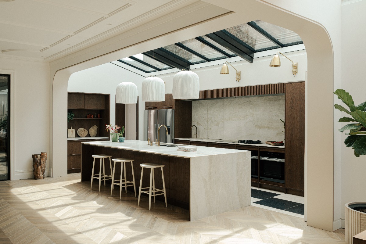Modern kitchen design with wood furniture, an island, and glass roof extension.