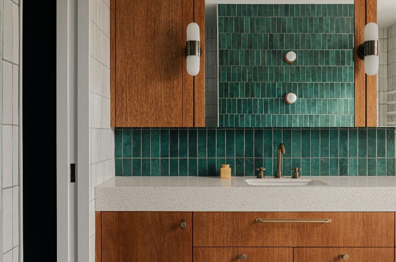 A modern ensuite in a London home with wood furniture, black and white floor tiles, and green wall tiles.