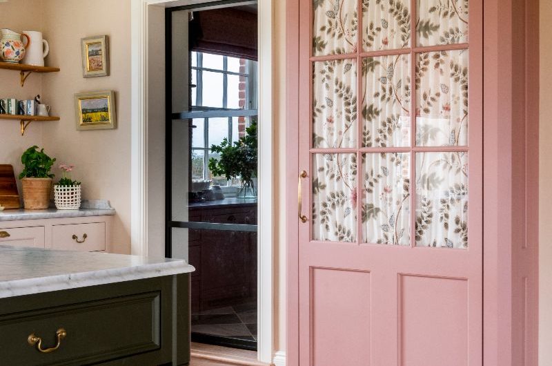 A charming glazed dresser with floral fabric hiding a fridge in a classic kitchen.