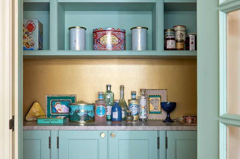 A closeup of the walk-in pantry with blue painted cabinetry and a metallic splashback.