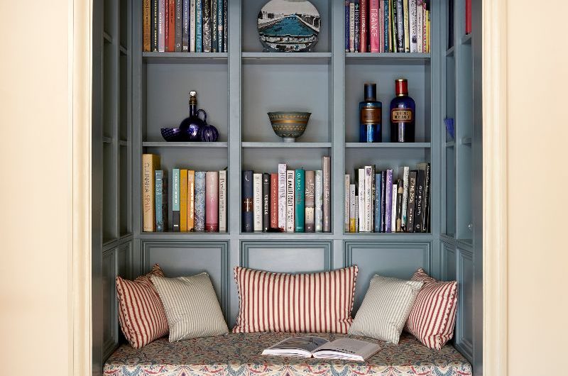 A reading nook with blue furniture, seating bench with patterned upholstery and storage drawers.