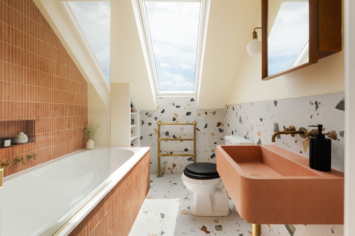 Bathroom design with specked flooring, kitkat tiles in a terracotta colour on a fitted bath and its wall, and a matching concrete basin on the opposite wall.