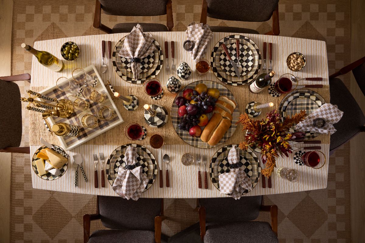 View of a luxury dining table with checkered plates, matching decor, and brown and white checkered napkins.