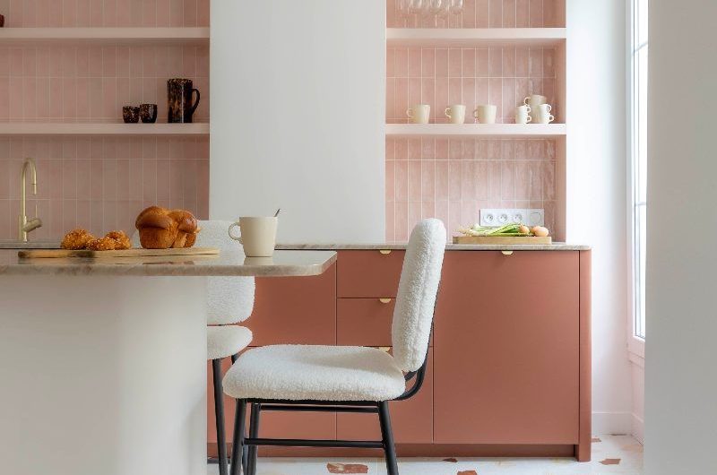 Modern kitchen with terracotta cabinets, a white island with breakfast bar and terrazzo flooring.