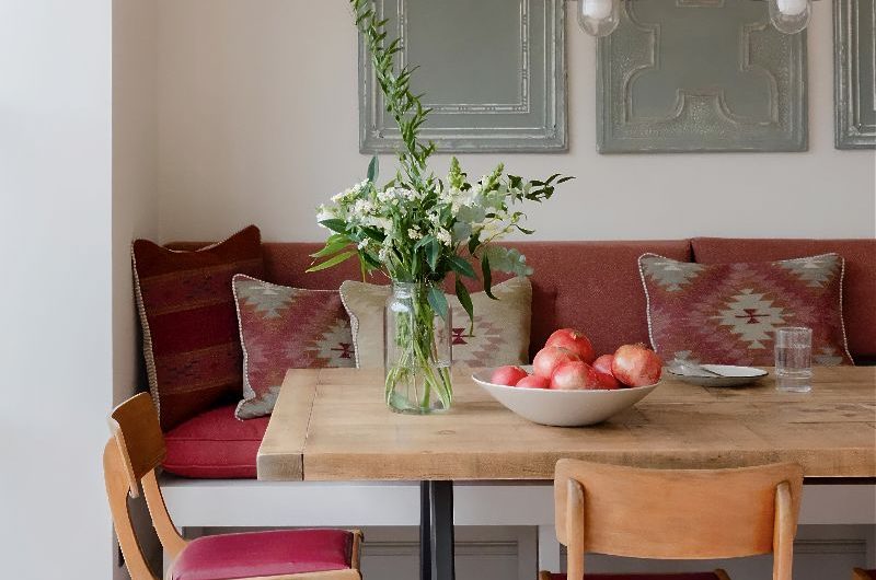Dining zone with a wood table, banquette seat, wood chairs, and wall art.