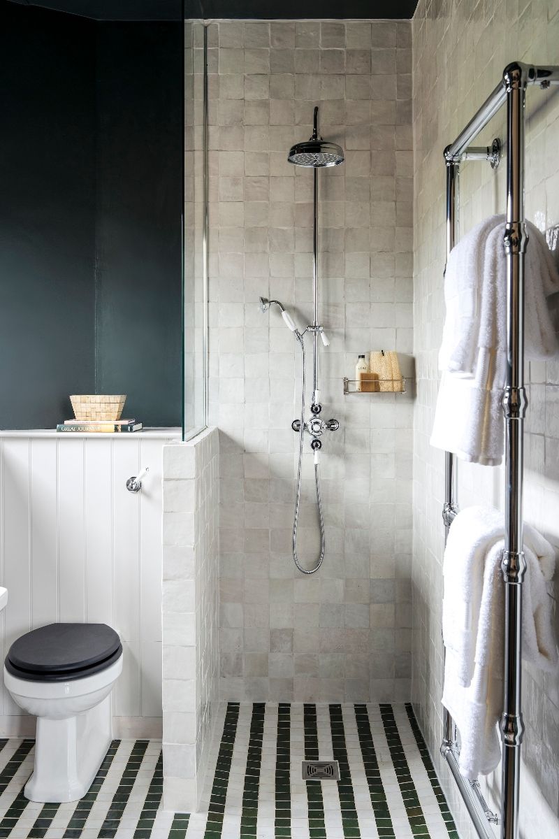 Shower design separated by a pony wall, decorated with zellige tiles and chrome brassware.
