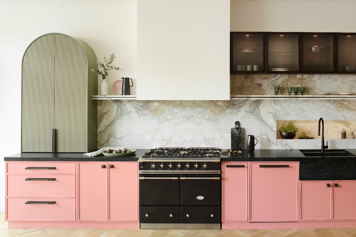 A cabinetry run with modern Shaker and fluted doors, statement marble, black worktops, matching sink, tap and range cooker, and LED strips.