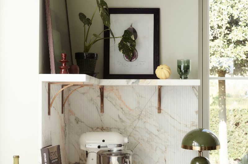 Closeup at open shelves supported by brass brackets, with minimalist decor.