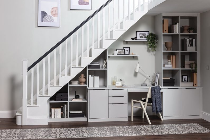 An under-the-stairs office solution with storage, open shelves, a desk and chair.