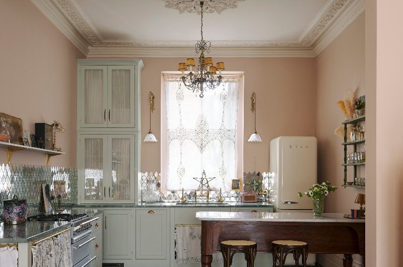 A classic kitchen design with vintage pendants, a wood freestanding table, Shaker cabinetry, pops of pastel and a retro fridge.