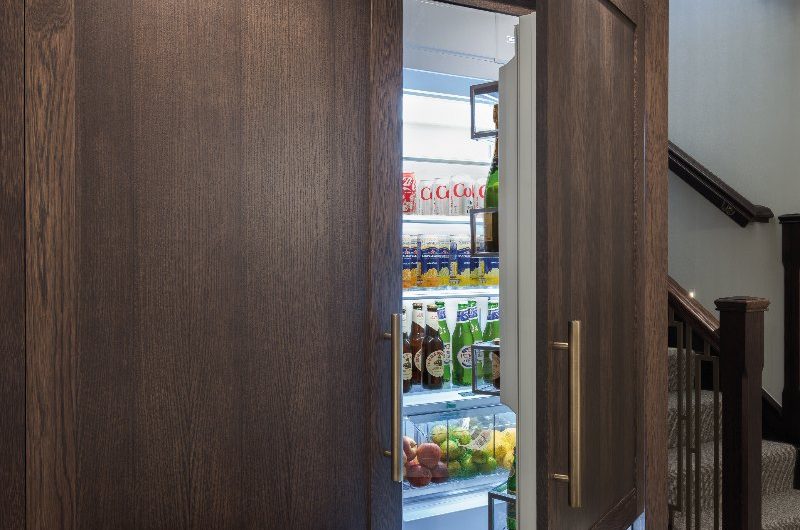 Hidden fridge within wood cabinetry with sleek brass handles.