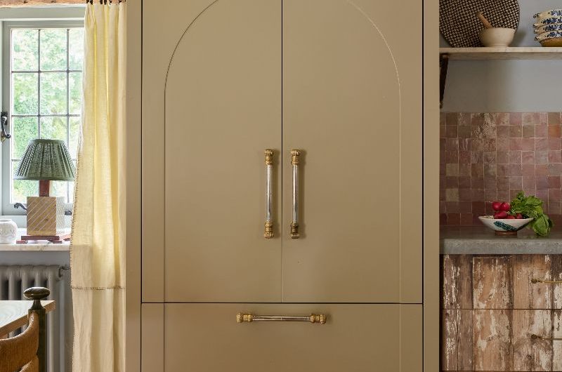 A bespoke fridge cabinet with intricate hardware and cornicing, painted in a neutral colour.