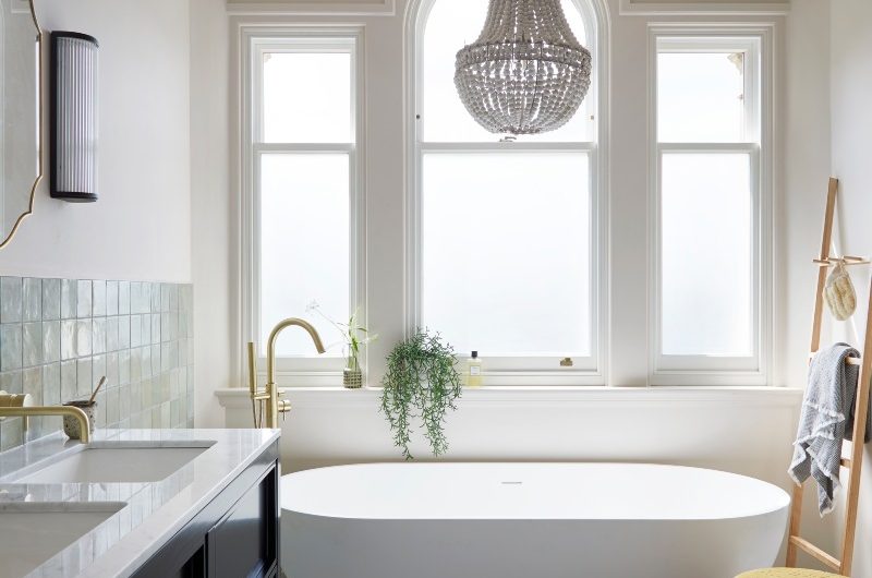 Modern scheme with marble floor tiles, a double vanity unit, and a freestanding tub under a window.