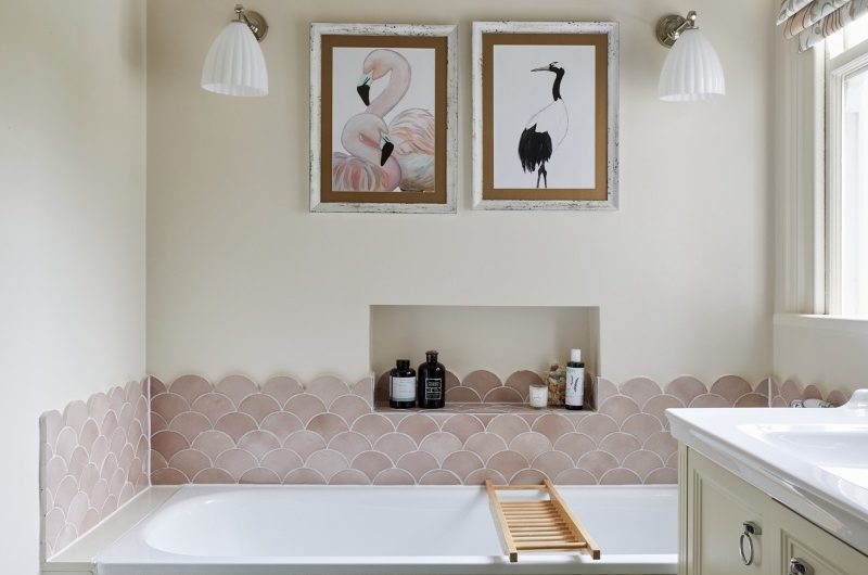 Bathroom design with pretty scallop tiles, storage niche, fitted tub, and a neutral vanity.
