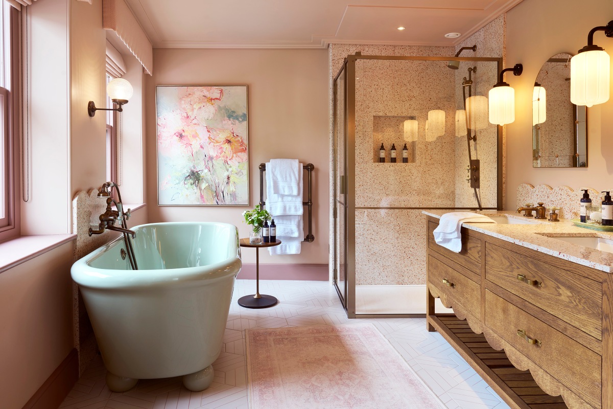 Pink bathroom design with a pastel blue freestanding tub, a shower zone with terrazzo surfaces, wood vanity unit, and bronze brassware.