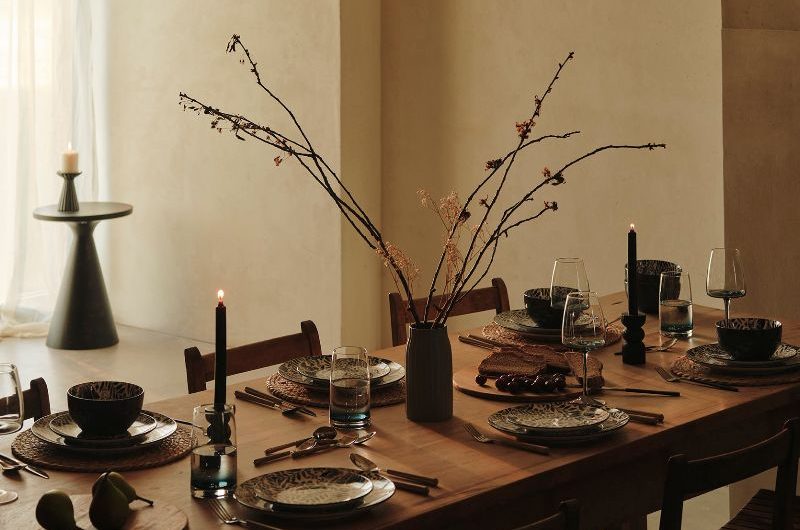 A Scandi style dining room with wood table and chairs, patterned plates, wood boards, and minimalist decor.