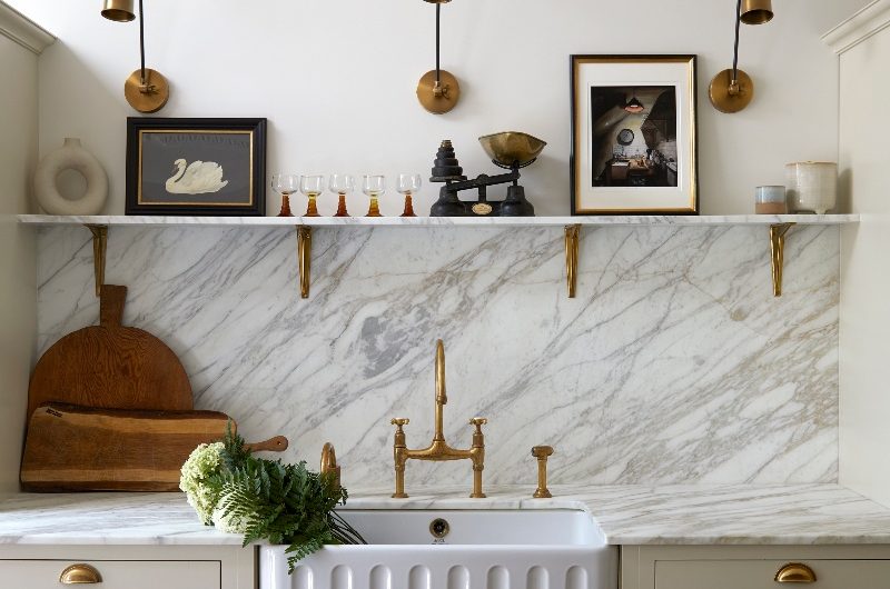A kitchen sink area with marble surfaces and a fluted butler sink.