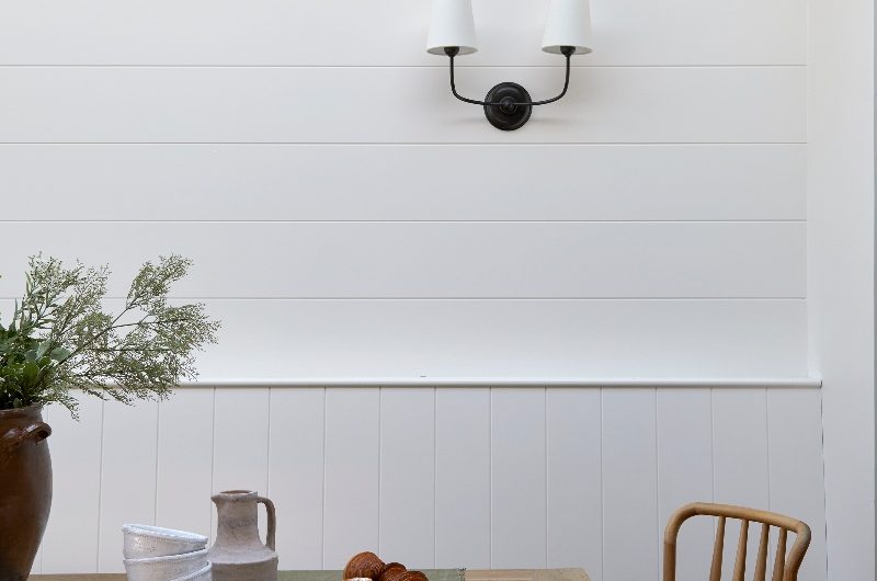 A dining area with wall panelling and wood table and chairs.