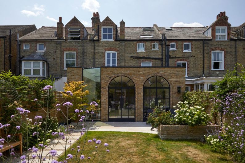 Outside view of the Victorian home with arched windows and a glass extension.