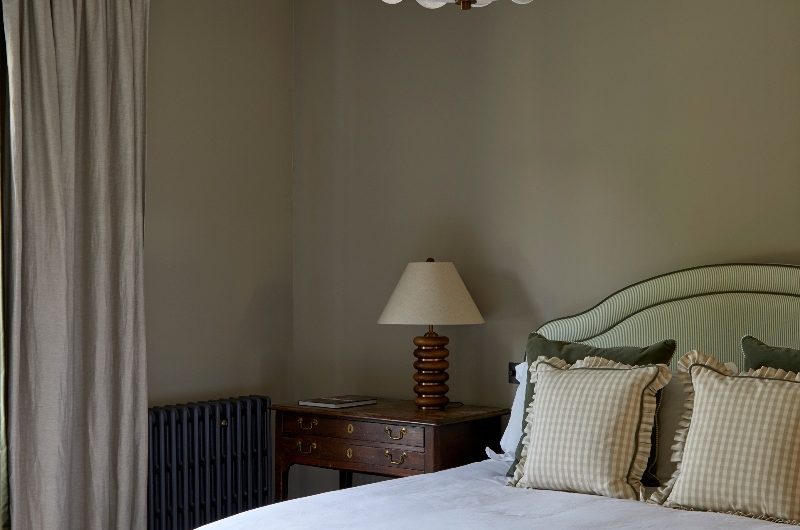 A calming bedroom in a north-facing room with a striped bed, wood vanity, and statement ceiling light.