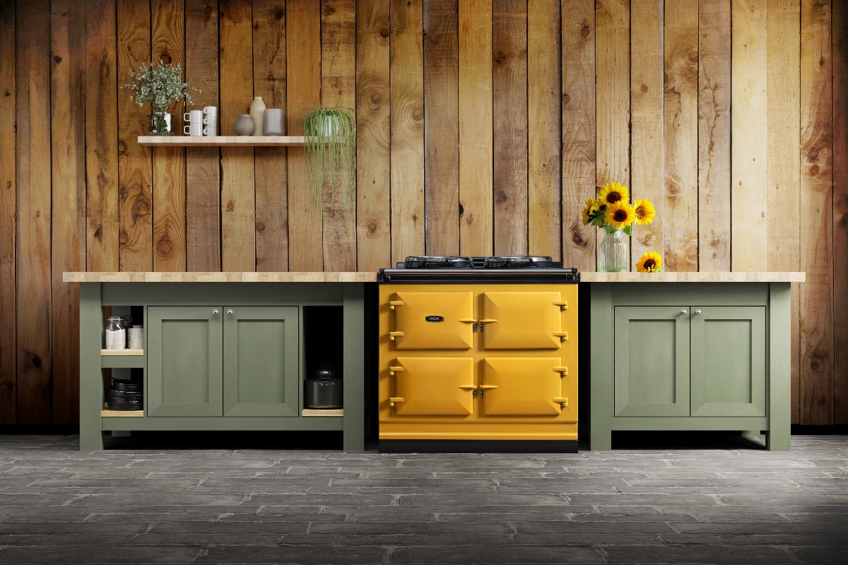 A country chic space with wall panelling, green furniture and a mustard coloured range cooker.