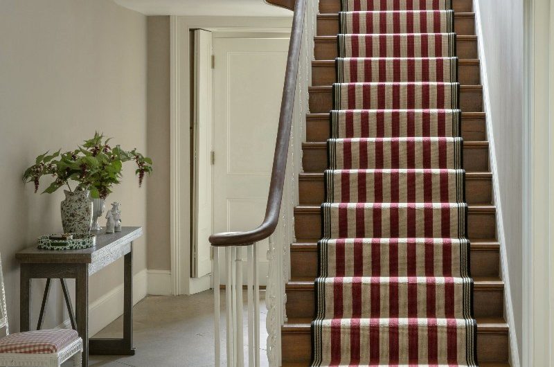 Entryway with stairs leading to the second floor with striped carpet.