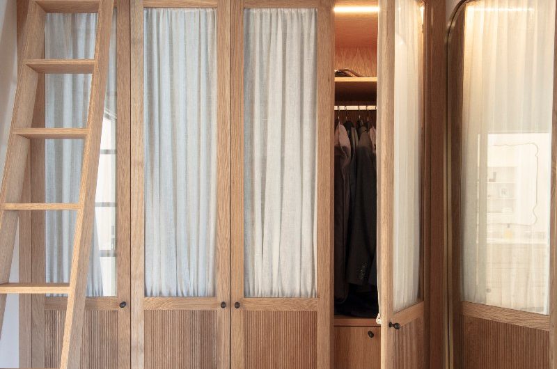 Wood floor-to-ceiling wardrobes with built-in lighting and a ladder.