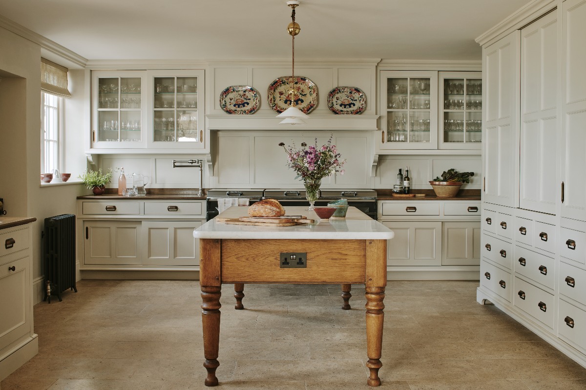 A historic home with a classic kitchen, a freestanding wood island topped with marble surfaces and stone flooring.