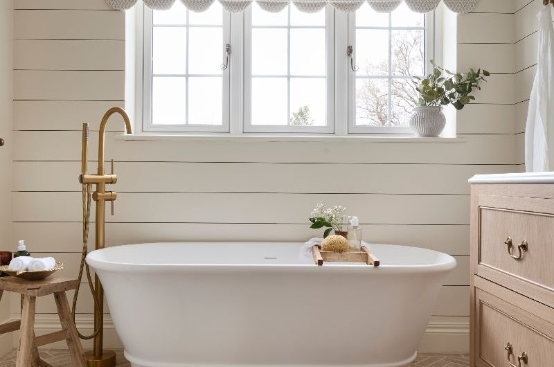 A classic bathroom scheme with horizontal wall panels painted in white and a freestanding tub, with terracotta tiles on the floor.