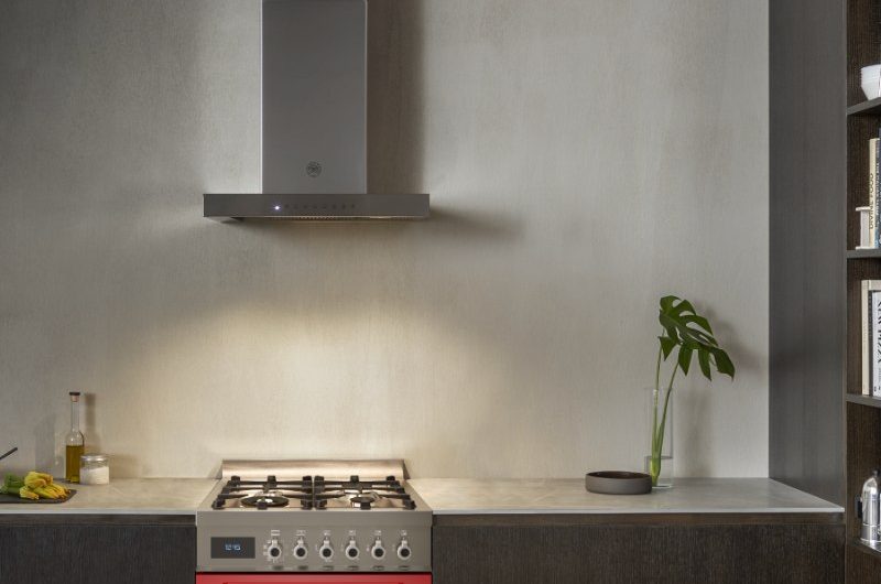 A wood kitchen with a compact, coloured range cooker and a sleek extractor hood.