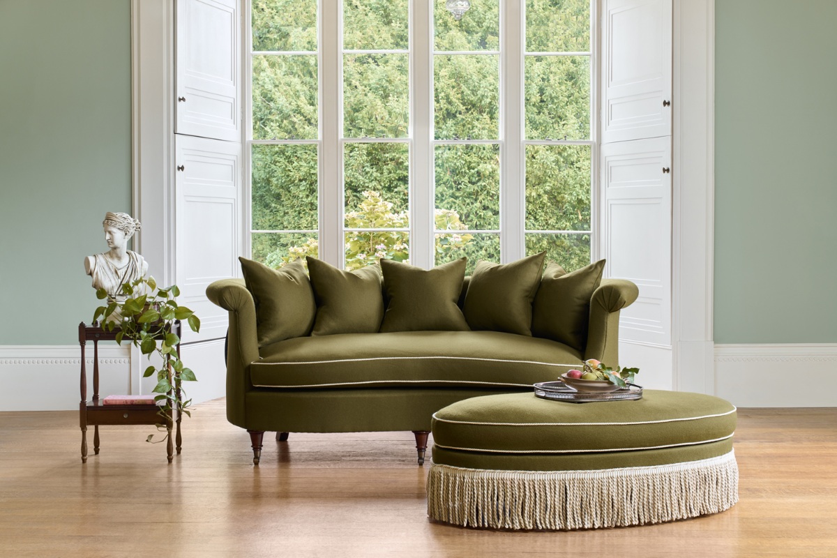 Classic scheme with a green sofa and matching frilled ottoman.