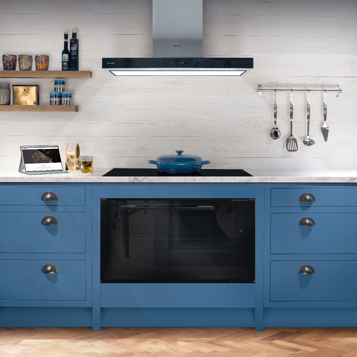 Blue kitchen design with a built-in oven, induction hob, and an extractor hood.