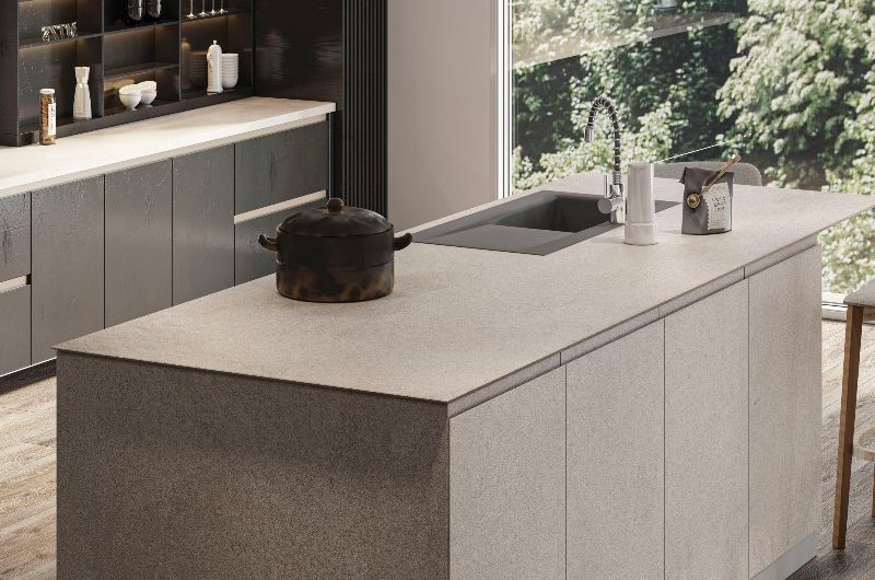 A neutral, sleek kitchen design with handleless units, wood flooring, a central island = with an invisible hob and sink and tap.
