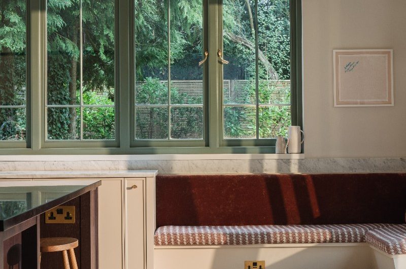 A classic scheme with neutral paint and cabinetry, built-in banquettes, marble surfaces and green painted windows.