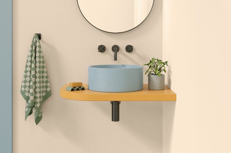 Bathroom design with a blue concrete basin on a mustard countertop.