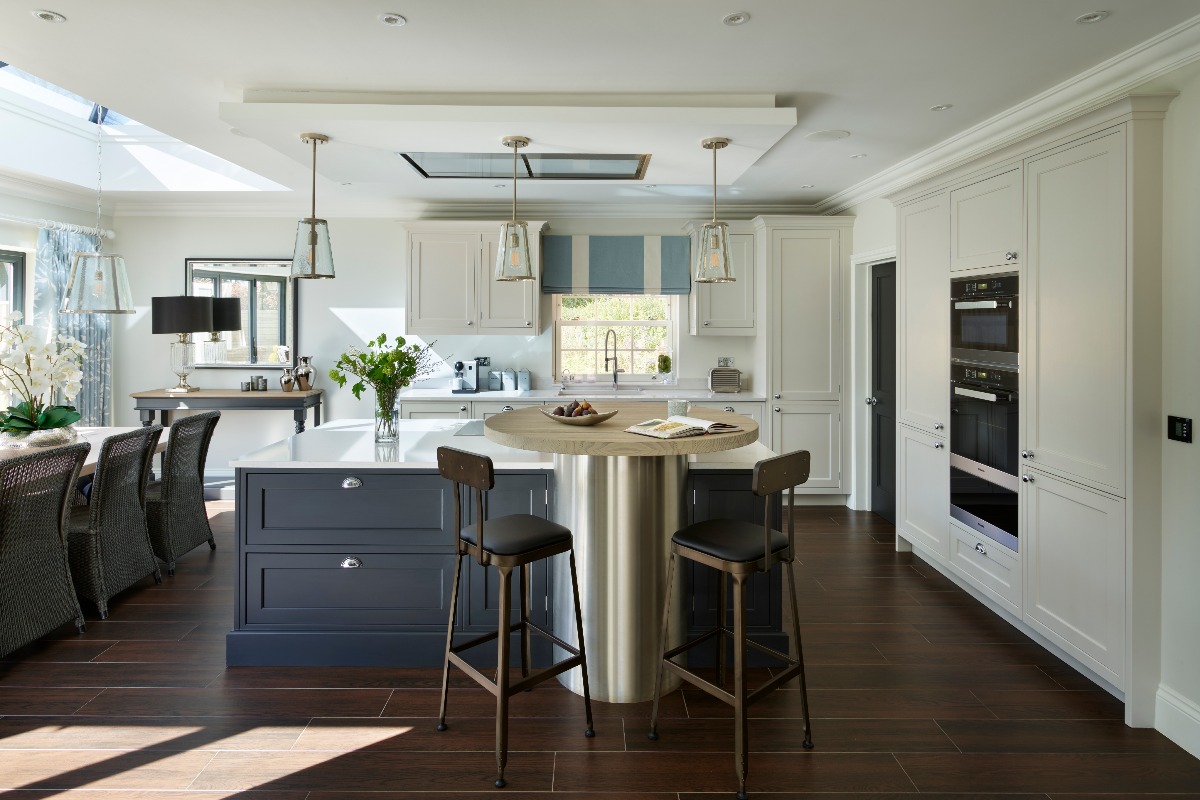 An L-shaped kitchen design with built-in appliances, ample storage, a central island with an elevated, round breakfast bar with stools and an adjoining dining area.