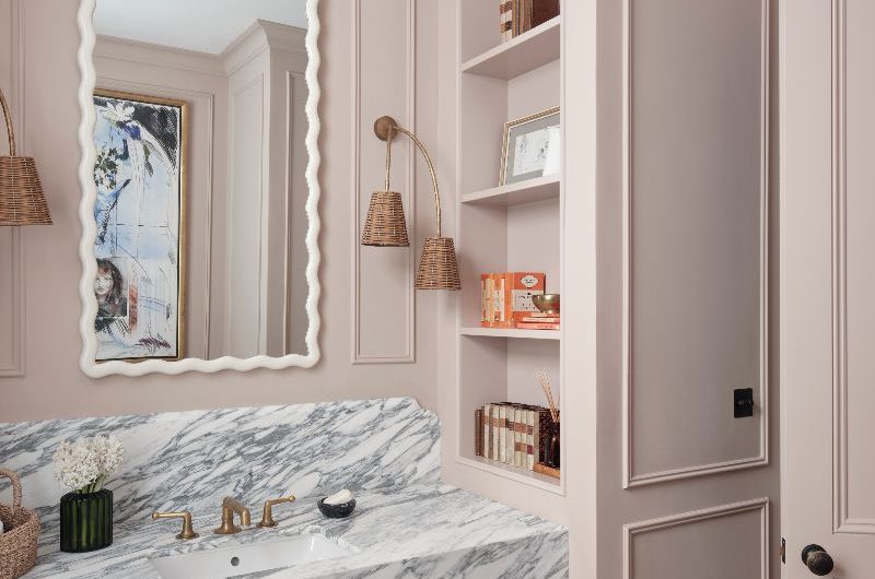 A luxurious bathroom design with a marble sink and storage shelf, quirky decor, and stone flooring.