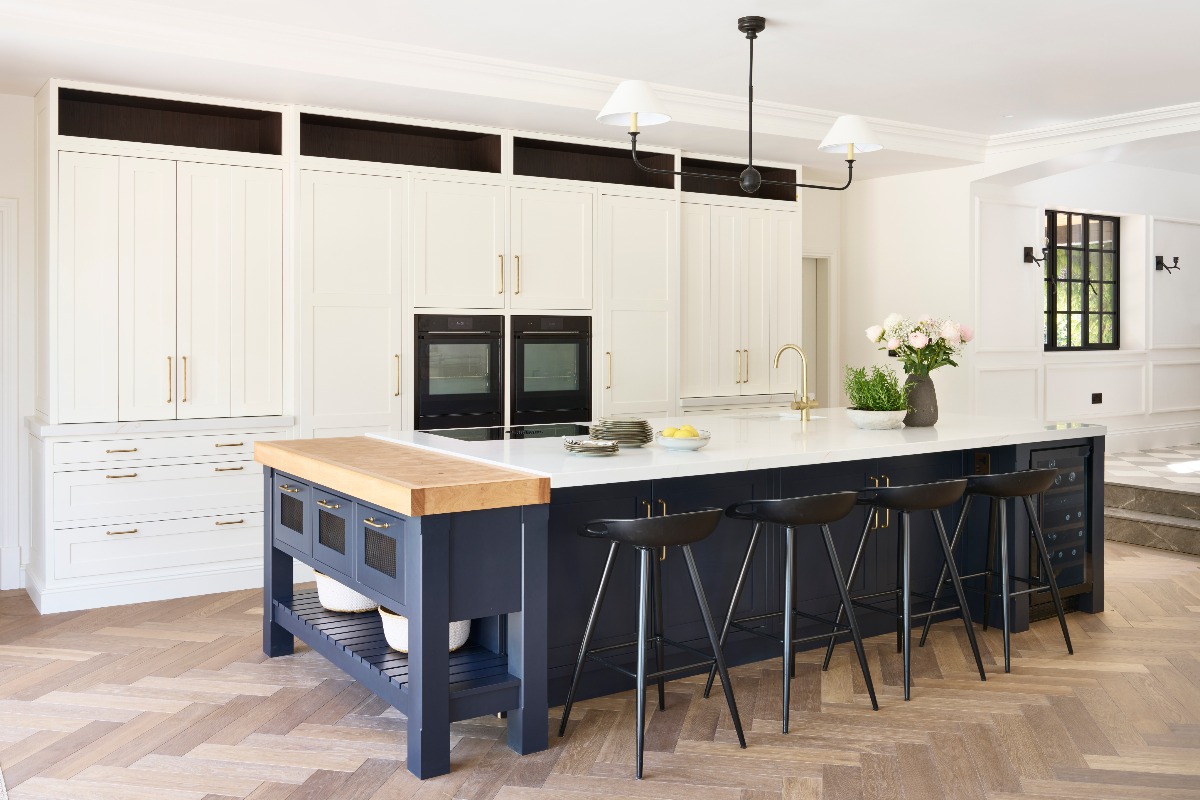 A bright room with floor-to-ceiling white cabinetry, a blue central unit with a bespoke pastry bench and a built-in sink and tap.