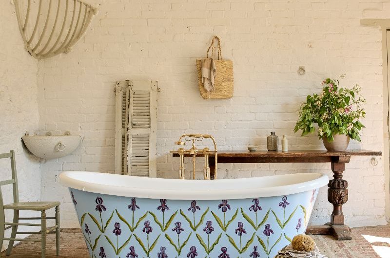 A painted bath with floral patterns and a blue background, with exposed brick on the walls and floors and natural decor.