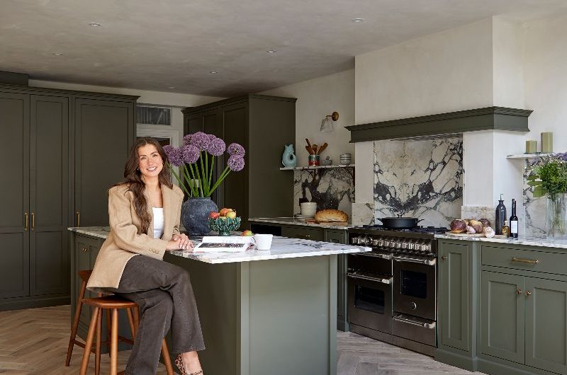 Homeowner posing on a stool next to her kitchen island.