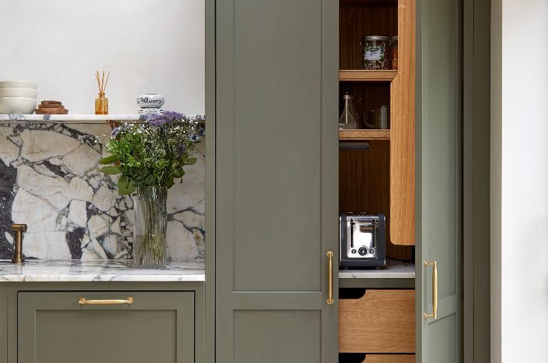 A double door pantry with wood interiors, drawers and hidden sockets for small appliances.