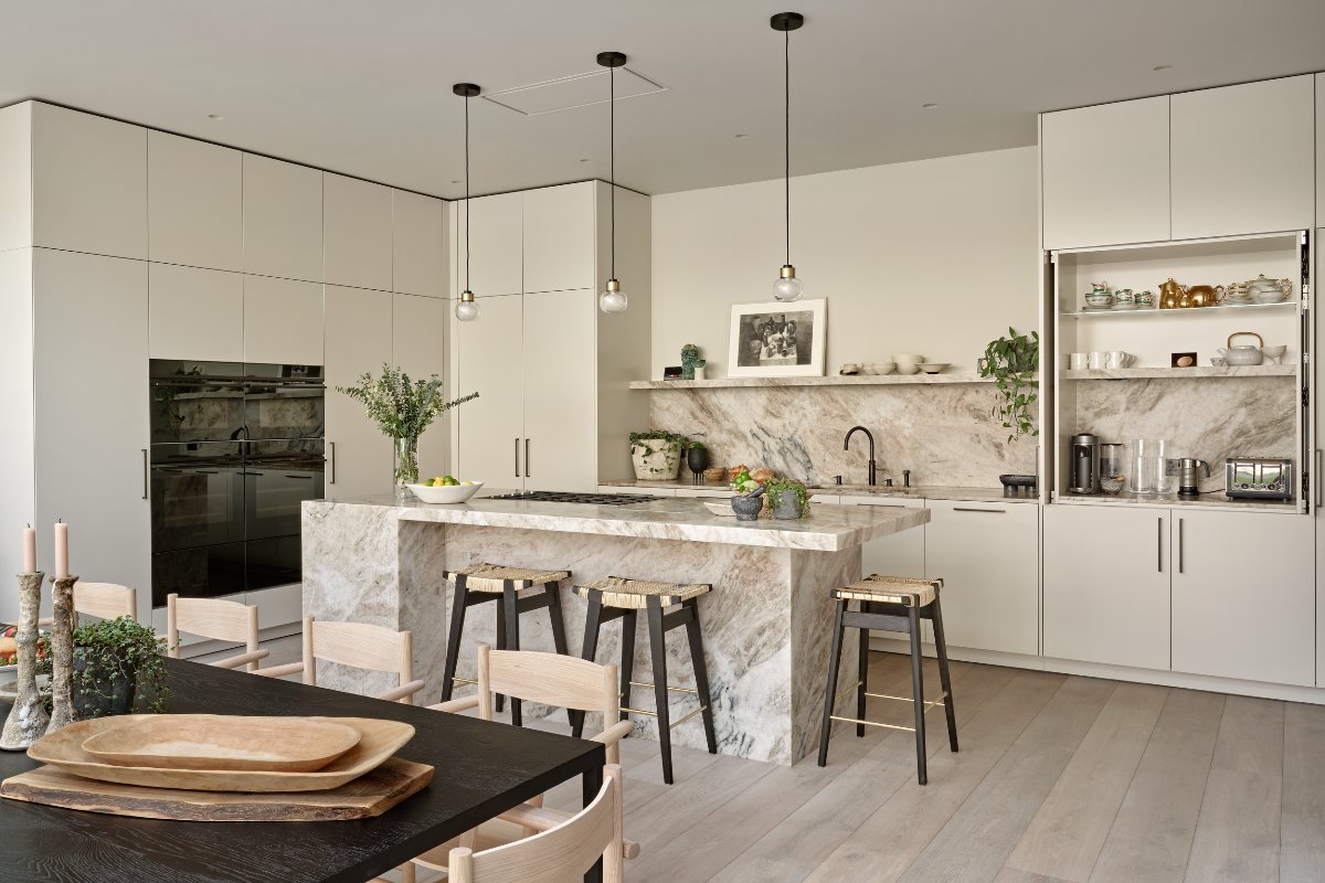 L-shaped kitchen design with tall cabinetry, stone surfaces, a stone island, and sleek handles.
